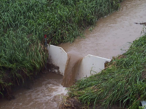 A v-notch weir showing runoff from agricultural fields during a storm event.